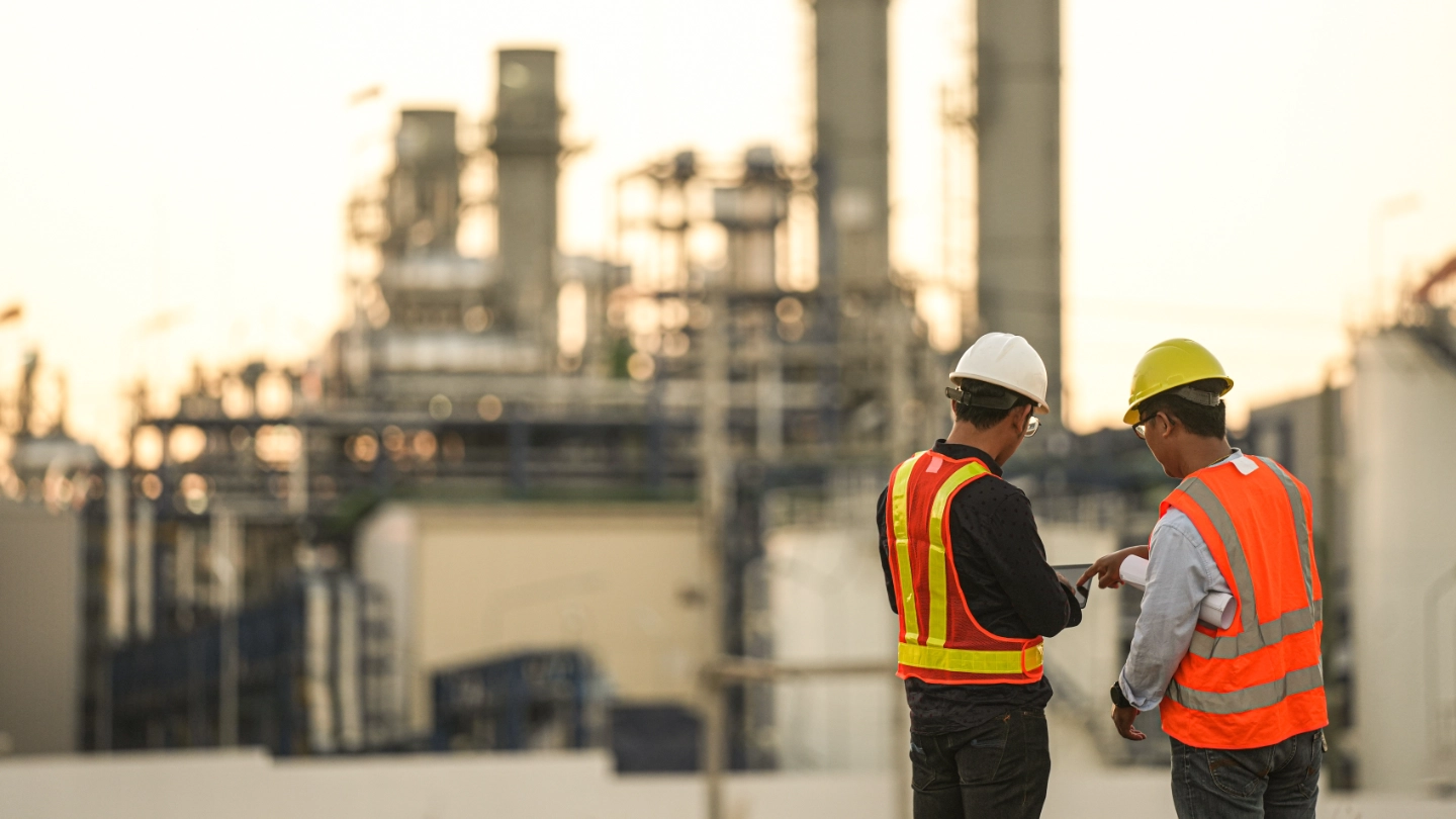 Two workers in front of a chemical plant image