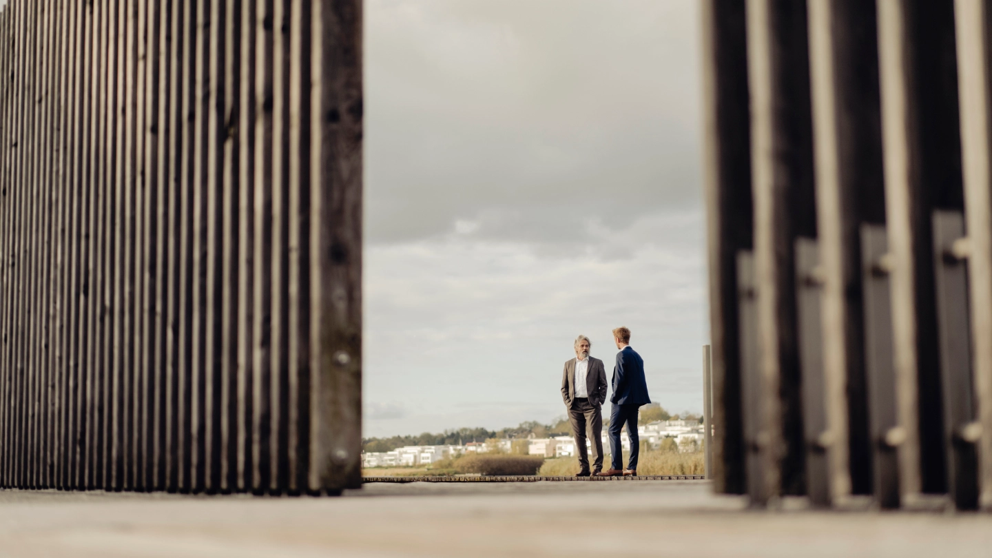 Two businessmen standing behind fencing Two businessmen standing behind fencing