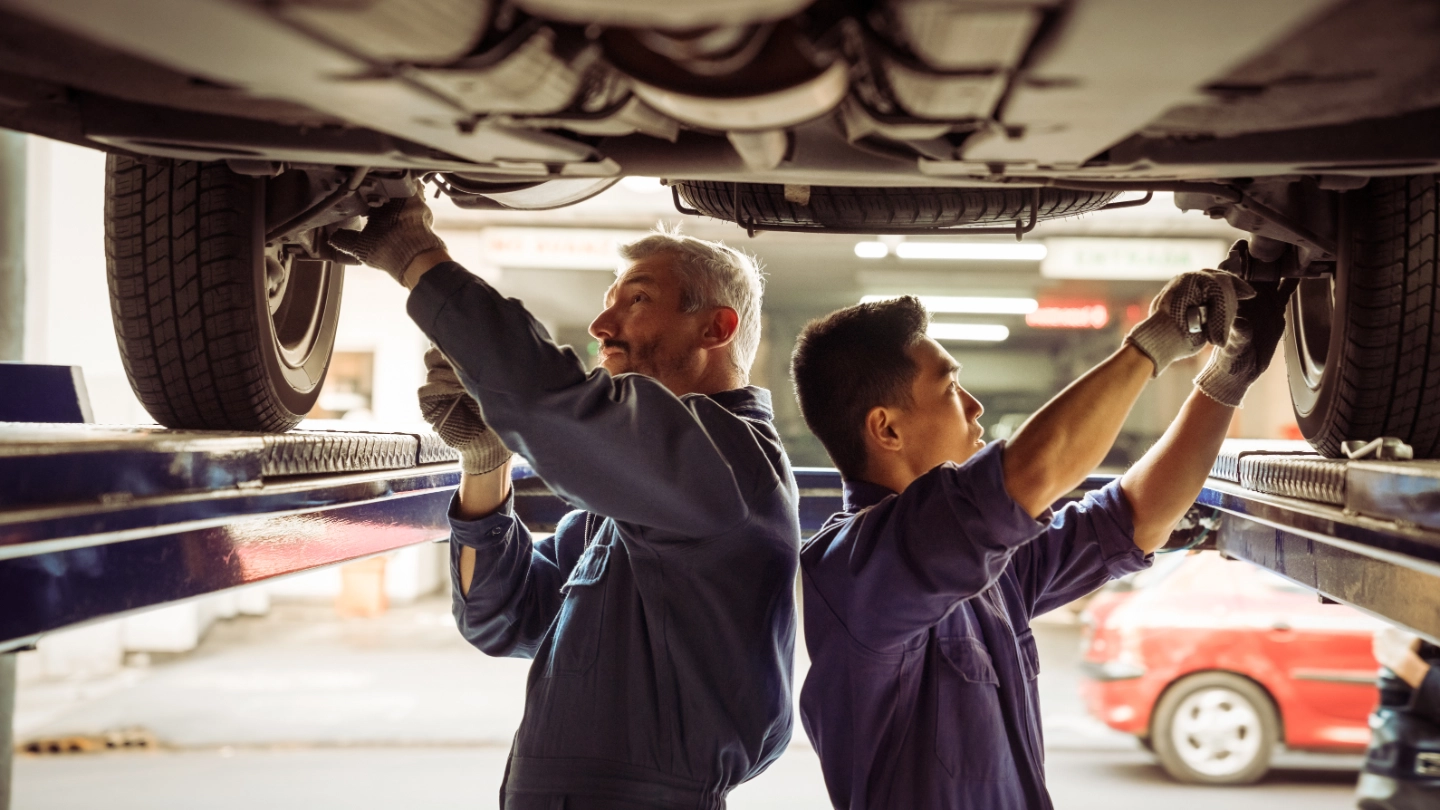 Two mechanics working underneath a car Two mechanics working underneath a car