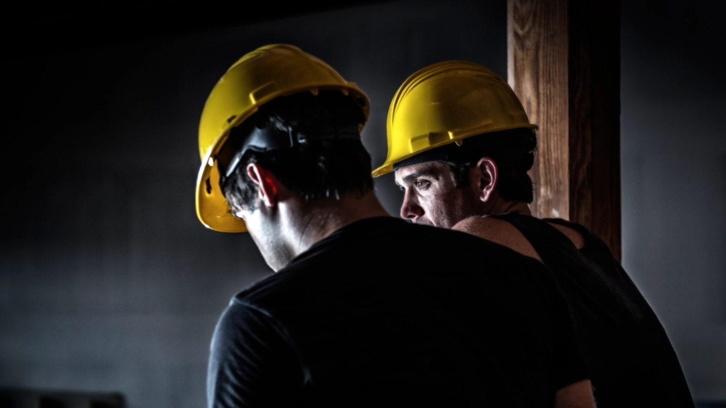 Two construction workers wearing yellow helmuts Two construction workers wearing yellow helmuts