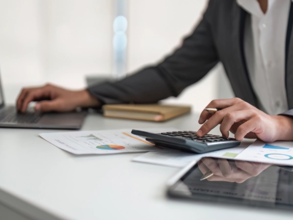 person using a calculator and laptop